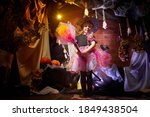 Small photo of Little cute blonde girl looking as witch in special dress and hat in room decorated for Halloween. Witchcraft and wizardry in carnival. Halloween style photo shoot