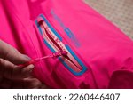 Small photo of Kirov, Russia - January 16, 2023: Ski jacket sleeve with zipper, logo and hand. Pink beautiful ski jacket for sale in private room, in atelier or store. Inept shooting of clothes for sales