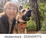 Small photo of A girl or a woman and German shepherd or Eastern European Shepherd dog in the forest, in nature, on a spring, summer, or autumn day. The concept of friendship between humans and animals