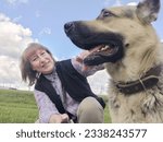 Small photo of A girl or a woman and a German shepherd or Eastern European Shepherd dog in the forest, in nature, on spring, summer, or autumn day and blue sky. The concept of friendship between humans and animals