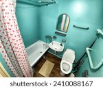 Small photo of The interior of a small, modest bathroom with a bath and a toilet. Green walls, curtains with red dot. The concept of poverty and conciseness