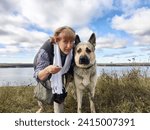 Small photo of Adult girl with shepherd dog taking selfie in forest. Middle aged woman and big shepherd dog on nature. Friendship, love, fun, hugs