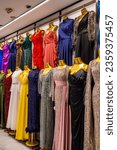 Small photo of colorful evening dresses on metallic gold female mannequins lined up in front of the wall in women clothing store, retail in Kayseri Turkey, Kitsch in fashion