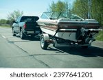 Small photo of NISSWA, MINNESOTA USA - MAY 15, 2022: Green Chevy Silverado towing a classic Hank's Sea Ray Seville's speed boat with a powerful inboard motor on the highway.