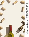Small photo of Frame from wine corks, vintage corkscrew and red wine bottle on beige background with shadows at sunlight. Minimal style layout with bottle cork, old bottle opener, design concept for wine list