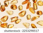 Small photo of Amber stones on light beige background, minimal monochrome seamless pattern, transparent stone yellow beige color. Natural gemstone mineral. Top view Amber textured fon. Nature gems at sunlight