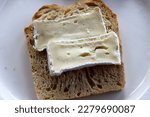 Small photo of a puristic meal: a slice of light bread topped with two slices of camembert.