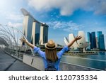 Young woman traveler with backpack and hat traveling into singapore city downtown. Travelling in Singapore concept