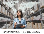 Portrait of happy young attractive asian entrepreneur woman looking at inventory in warehouse using smart tablet in management technology,  interconnected industry, asian small business sme concept.