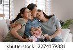 Small photo of Mother day two grown up child cuddle hug give flower gift box red heart card to mature mum. Love kiss care mom asia middle age adult three people sitting at home sofa happy smile enjoy family time.