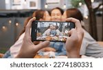 Small photo of Young adult asia people hug cuddle kiss love care for mom taking photo selfie video on mobile phone camera at home picnic dining fun night party dine table. Relax older mum smile enjoy warm time meal.