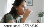 Small photo of Asia people young woman happy relax smile sit at home sofa drink water take birth control pill pouring folic preconception drug bottle or weight loss diet capsule. Body skin health care sick relief.