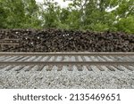 Brown railroad ties piled up next to active train tracks