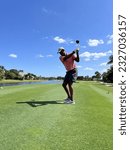 Small photo of African American, Black left-handed golfer on beautiful country club golf course