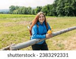 Small photo of Happy redhead Woman in active trekking clothes having a halt after hiking. Hiker drinking water from water bottle or hot drink from yellow thermos