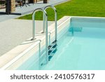 Small photo of Grab bars ladder in the blue swimming pool. Ladder stainless handrails for descent into swimming pool. Vacation concept