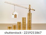 Small photo of Stacking gold coins with increase and tower crane and hoist brake solutions with build new house in the office, Saving money and loan for construction real estate and home concept.