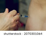 Small photo of Injection with a syringe into the body. Self-medication at home. Medical disposable syringe with vaccine in hands without gloves.