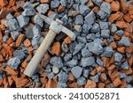 Small photo of Stones made from broken red bricks and concrete blocks. Hammer pickaxe on a pile of stones.