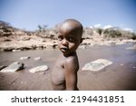 Small photo of West Pokot, Kenya - 01.26.2017: A missionary team from a charitable foundation came to help homeless children. Hunger and unemployment in Africa. Portrait of an African American child.