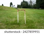Small photo of Ground level view of a metal croquet loop seen in the grounds of a large, private house.