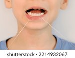 Small photo of funny little boy flossing his teeth. soft thread of floss silk or similar material used to clean between the teeth