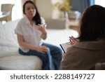 Small photo of caring psychologist listens empathetically to her patient during a therapy session. She takes detailed notes, providing emotional support and guidance to help her patient overcome personal challenges