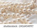 A string of natural pearls lay elegantly on a pale canvas, their soft focus creating a dreamy atmosphere. This image evokes a return to natural beauty amidst the modern era's harsh synthetic