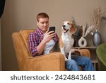 Small photo of Engrossed in his phone, the man finds company with his loyal dog; their bond unshaken by the distractions of technology.
