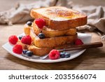 plate of french toasts with fresh berries on a wooden table