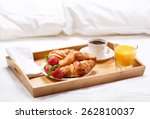 breakfast in bed with coffee, croissants, strawberries and juice
