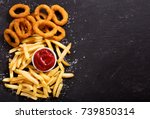 onion rings and french fries with ketchup on dark table, top view