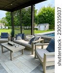 Small photo of Breathtaking outdoor living entertainment space and patio under a pavilion pergola - poolside and equipped with bar and gas fire pit that has a cascading waterfall. Includes couches and television .