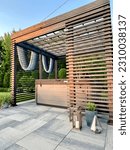 Small photo of Gorgeous modern boho backyard design showcasing an outdoor pergola made from pine. Within the pergola sits a hot tub spa with seats and a lounger. Artsy decor sets the mood with outdoor LED lights.