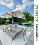 Gorgeous outdoor living backyard patio with pergola, outdoor rug,  tequila bar, dining set, couch, television, pool with waterfall , fire pit and stunning Techo Bloc patio pavers