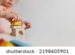 Small photo of Adorable little child girl of preschooler age playing wooden building blocks at home or kindergarten. Toddler kid is stacking a tower from colourful cube toys on the table. Kids Play Room. Banner size