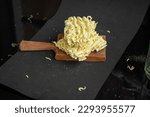 Small photo of Block of uncooked noodles with a wooden butting block on a black background in studio 74UZJGHMBZU