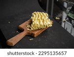 Small photo of Block of uncooked noodles with a wooden butting block on a black background in studio