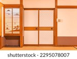 Wall of a typical traditional Japanese room featuring tatami mats covering the floor, fusuma doors and shoji window made of rice paper with wooden decorations evocating a landscape of the mount Fuji.