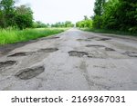Small photo of A snapshot of old cracked asphalt in need of repair. The road is full of holes and potholes.