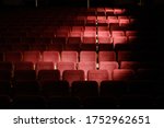 Rows of Emply Red Theatre Seats with Descending Circles of Light Pouring in from the Windows and Dark Moody Shadows