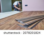 Small photo of Flooring work. worker joining vinyl floor covering at home renovation