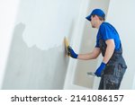 Small photo of refurbishment. Plasterer worker spackling a wall with putty