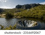 Discover the mesmerizing Covão dos Conchos, a captivating lake with a distinctive hole, nestled in Serra da Estrela, Portugal. Majestic rocks and lush bushes frame this enchanting natural wonder.