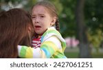 Small photo of little child cries, tears child face, mother calms capricious kid girl daughter, happy family, wipe tears face, hug kid park, child love, trying control process, strong emotion, serious difficulties