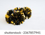 Gold and black cheerleading pom-poms on white practice mat. Background
