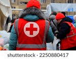 Small photo of Dnipro Ukraine 2023-01-14. Red Cross volunteers help wounded near destroyed house after Russian missile attack. Red cross sign on uniform of paramedic