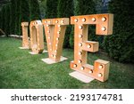 Wedding decor, LOVE letters. big love letters in light bulbs for photo booth at wedding reception in night outdoors. love word lights, stylish evening decor for wedding ceremony.