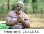 Small photo of Indian senior male having health issues and body pain suddenly in garden