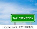 Small photo of Green color transportation sign with word tax exemption on blue sky with white cloud background